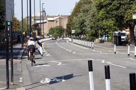 Photo showing a main road with people using a temporary cycle lane heading away from the camera.