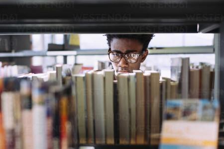 man-searching-books-in-shelf-at-library-