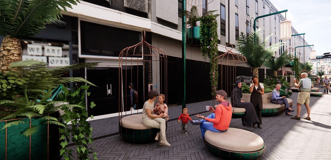 Families sitting in birdcage shaped seating amid trees and foliage on the pedestrianised Saville Row