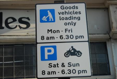 The shared use sign in use for goods vehicles loading only and taxis, the first part of the sign is the standard goods vehicle loading sign which has a picture of the loading/unloading symbol and states ‘Goods vehicle loading only Mon - Fri 8am – 6.30pm’, the second part of the sign has a picture of a motorcycle and states Sat & Sun 8am 6.30pm