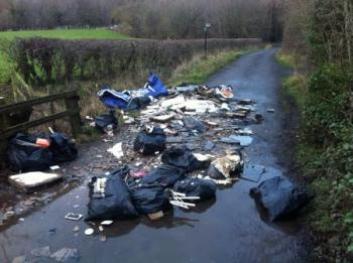 fly tip in road and puddle