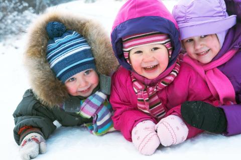 Three children smiling in the snow