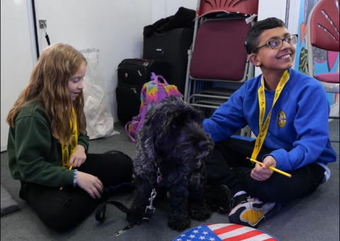 Two children sitting with a hearing dog for the deaf