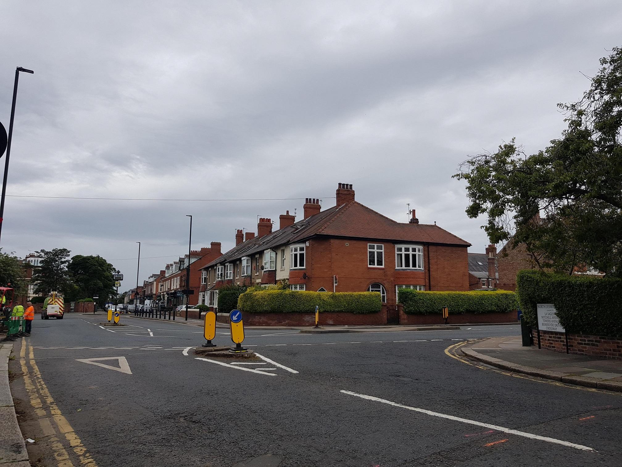 Photo showing a  junction between two roads with houses at the side of the road.