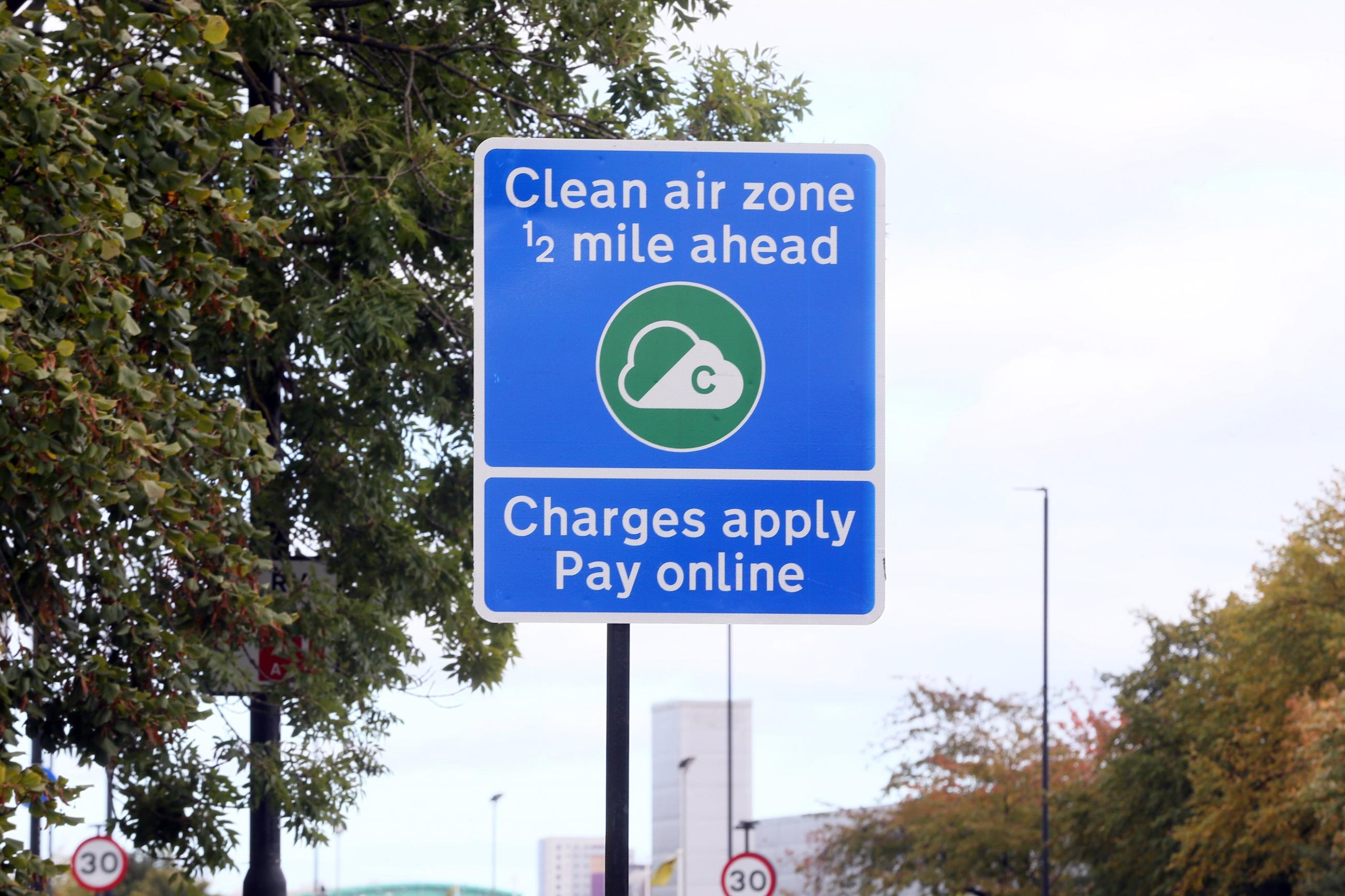A blue road sign with the words 'Clean Air Zone, half a mile ahead. Charges apply. Pay online.'